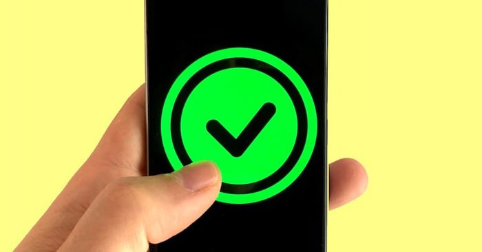 A hand holding a smartphone with a bright green checkmark inside a green circle displayed on the screen, indicating approval or success, against a solid yellow background. Partner with us and experience seamless efficiency.