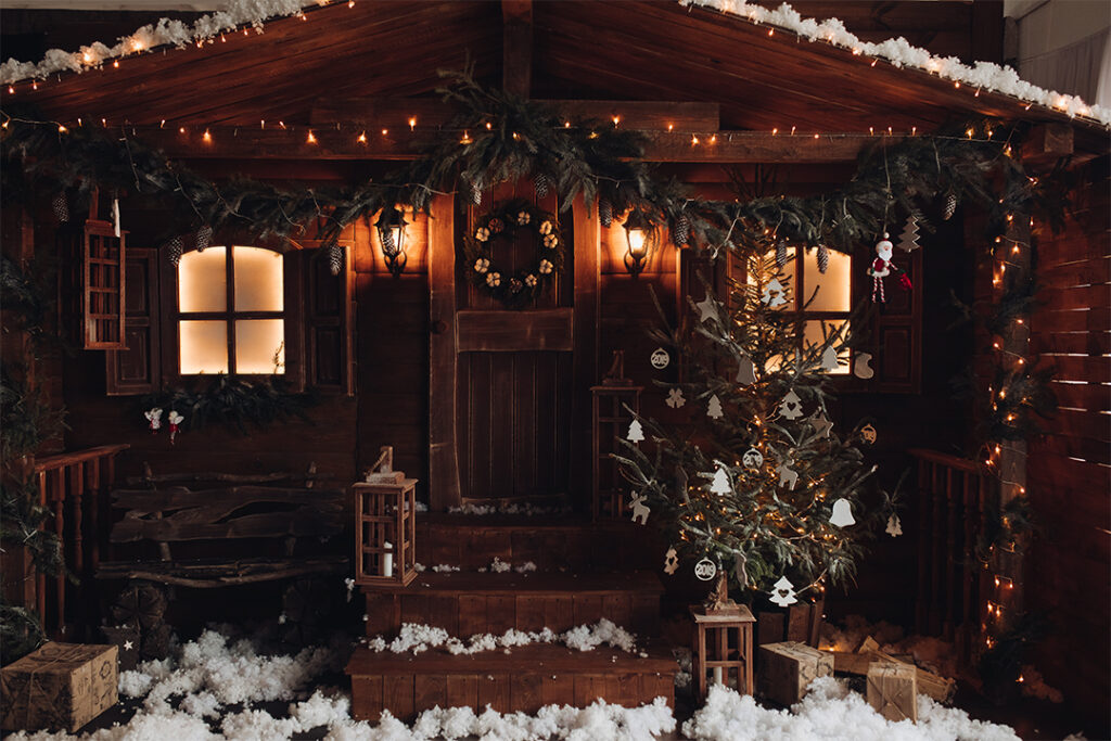 A cozy wooden cabin decorated for Christmas with warm lights, garlands, and a festive wreath on the door. A lit Christmas tree stands by the porch, surrounded by snow and wooden lanterns. Nearby, a SUDS Power Washing van ensures everything sparkles, enhancing the warm, festive holiday atmosphere.